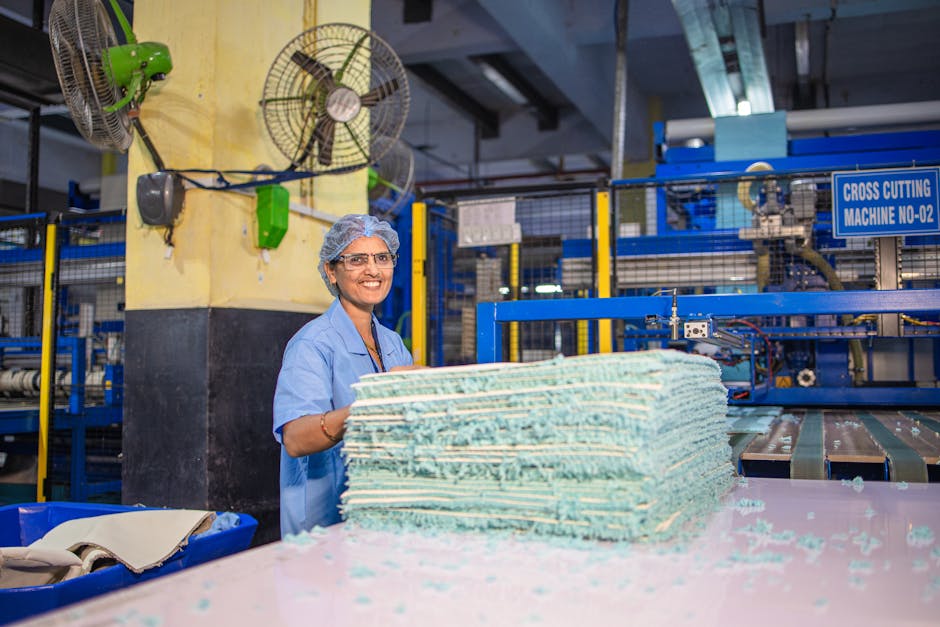 Happy female worker in textile factory smiling near cross cutting machine.