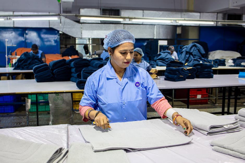 Female factory worker folding textiles in an industrial setting, showcasing blue-collar labor.